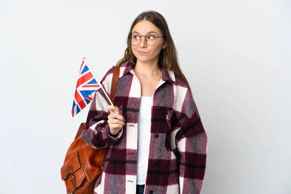 若いリトアニアの女性は白い背景に隔離された英国の旗を持っている疑問ジェスチャーを作る側を見て — ストック写真