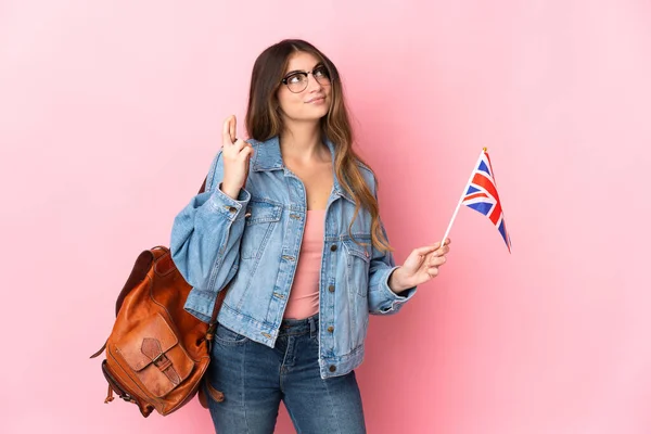 拿着英国国旗的年轻女子 背景为粉色 手指头交叉 祝愿好运 — 图库照片