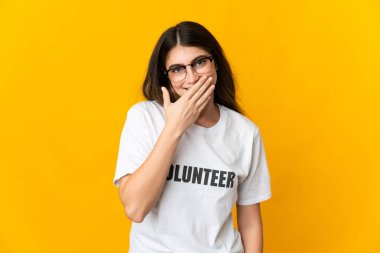 Sarı arka planda izole edilmiş genç gönüllü kadın mutlu ve gülümsüyor.