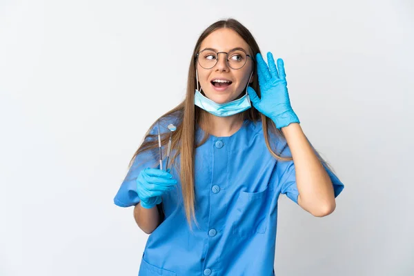 立陶宛女牙医把工具放在孤立的背景下 用手捂住耳朵听什么东西 — 图库照片