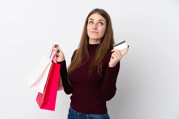 Jonge Vrouw Geïsoleerde Witte Achtergrond Met Boodschappentassen Een Creditcard Denken — Stockfoto