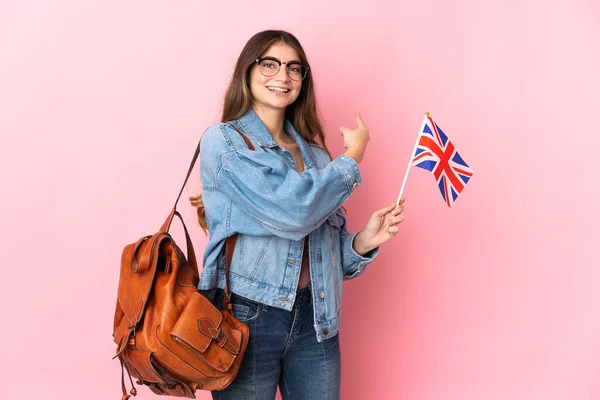 Молодая Женщина Держащая Флаг Великобритании Розовом Фоне Указывает Назад — стоковое фото