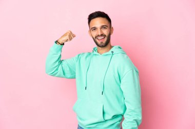 Pembe arka planda izole edilmiş genç beyaz adam güçlü bir jest yapıyor.