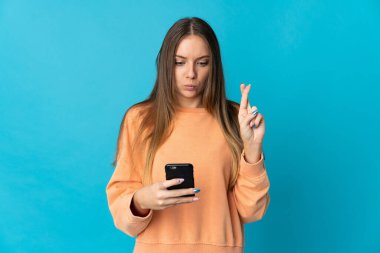 Genç Litvanyalı kadın mavi arka planda izole edilmiş. Cep telefonu kullanıyor.