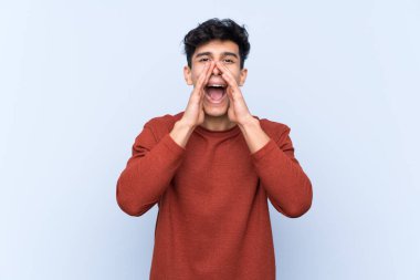 Arjantinli genç adam mavi arka planda bağırıyor ve bir şey duyuruyor.