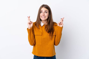 İzole edilmiş beyaz arka planı olan genç bir kadın parmaklarını çapraz yapıp en iyisini diliyor.