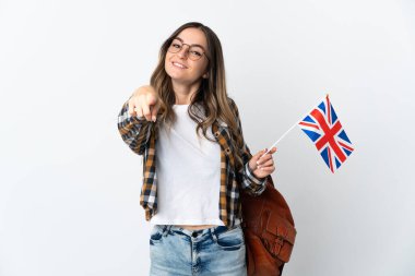 Genç Romen kadın, beyaz arka planda izole edilmiş bir Birleşik Krallık bayrağını elinde tutarken mutlu bir ifadeyle ön tarafı işaret ediyor