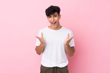 Arjantinli genç adam soyutlanmış pembe arka planda mutsuz ve bir şeyden hayal kırıklığına uğramış.