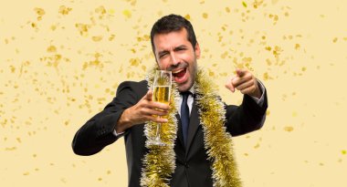 Şampanyalı bir adam yeni yılı kutlarken bir partide konfetilerle gülümserken seni işaret ediyor.