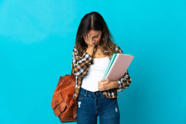 Genç bayan öğrenci mavi arka planda izole edilmiş, yorgun ve hasta bir ifadeyle.