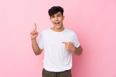 Arjantinli genç bir adam pembe arka planda şaşırmış bir yüz ifadesi var.