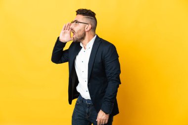 İzole edilmiş sarı arka planda ağzı açık bağıran bir iş adamı.