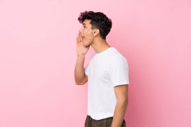 Arjantinli genç bir adam pembe arka planda ağzı açık bağırıyor.