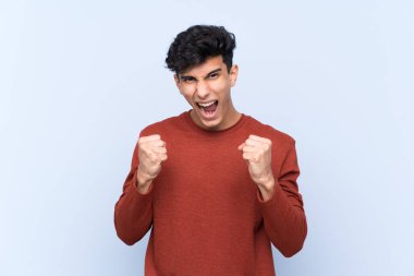 Arjantinli genç adam izole edilmiş mavi arka planda kötü bir durum yüzünden hayal kırıklığına uğradı.