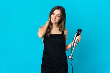 Mavi arka planda izole edilmiş el blenderi kullanan Romen kadın gülüyor