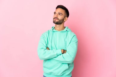 Pembe arka planda izole edilmiş genç beyaz adam yan tarafa bakıyor.