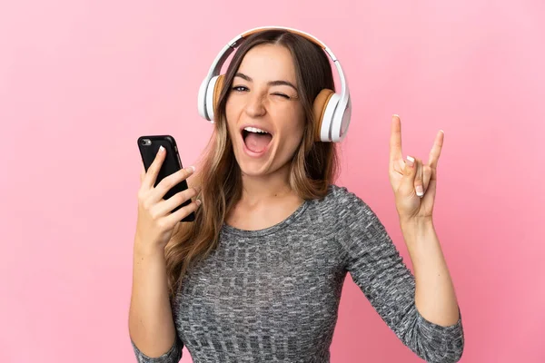 Молода Румунська Жінка Ізольована Рожевому Фоні Слухаючи Музику Мобільним Жестом — стокове фото