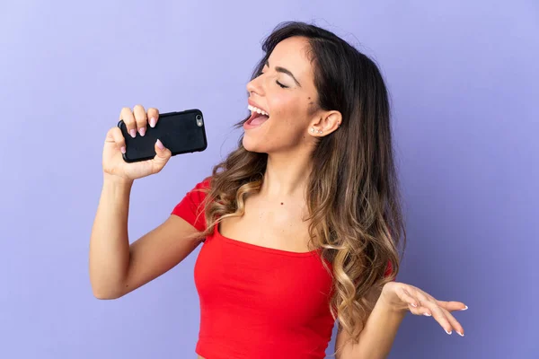 Mulher Caucasiana Jovem Isolado Fundo Roxo Usando Telefone Celular Cantando — Fotografia de Stock