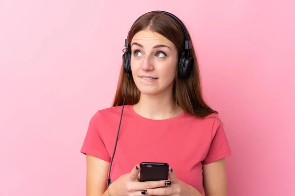 Jeune Femme Sur Fond Rose Isolé Écoutant Musique Avec Mobile — Photo