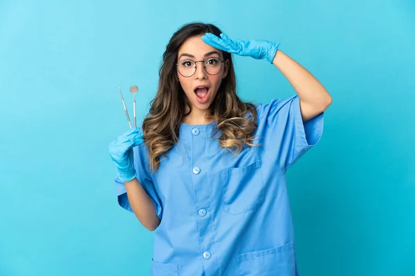 Zahnärztin Hält Werkzeug Mit Überraschendem Gesichtsausdruck Über Isoliert Auf Blauem — Stockfoto