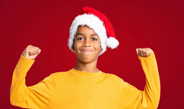 Afroamerikansk Pojke Med Jul Hatt Firar Seger Över Röd Bakgrund — Stockfoto