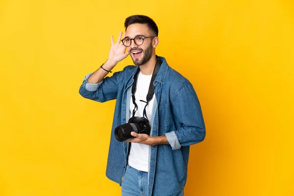 Junges Fotografenmädchen Isoliert Auf Gelbem Hintergrund Hört Etwas Indem Die — Stockfoto