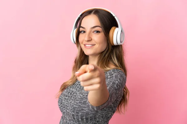 Jovem Romena Isolada Fundo Rosa Ouvindo Música Apontando Para Frente — Fotografia de Stock