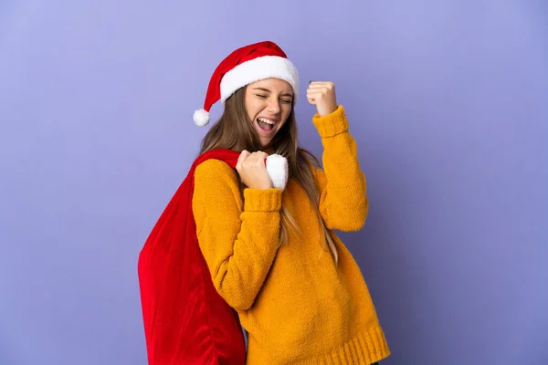 勝利を祝う紫色の背景に隔離されたクリスマスの帽子を持つリトアニアの女性 — ストック写真