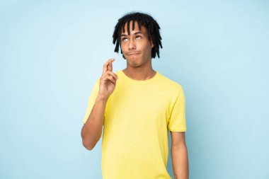 Genç Afro-Amerikalı adam mavi arka planda izole edilmiş, şans diliyor ve en iyisini diliyor.