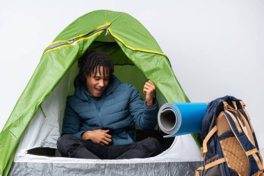 Genç Afro-Amerikan bir adam kamptaki yeşil çadırda gitar jesti yapıyor.