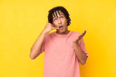 Genç Afro-Amerikalı adam sarı arka planda izole edilmiş telefon jestleri yapıyor.