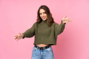 Soyutlanmış pembe arka planı olan genç bir kadın sunar ve davet eder.