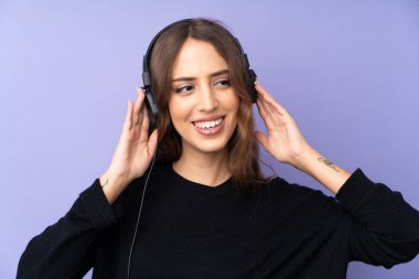 Soyutlanmış mor arka plan müzik dinleyen ve şarkı söyleyen genç bir kadın.