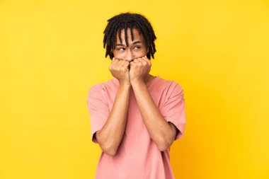 Genç Afrikalı Amerikalı adam sarı arka planda izole edilmiş gergin ve korkmuş bir şekilde elleriyle suni teneffüs yapıyor.