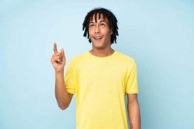 Genç Afrikalı Amerikalı bir adam mavi arka planda izole edilmiş ve şaşırmış.