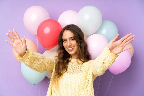 Mujer Joven Captura Muchos Globos Sobre Aislado Sobre Fondo Púrpura —  Fotos de Stock