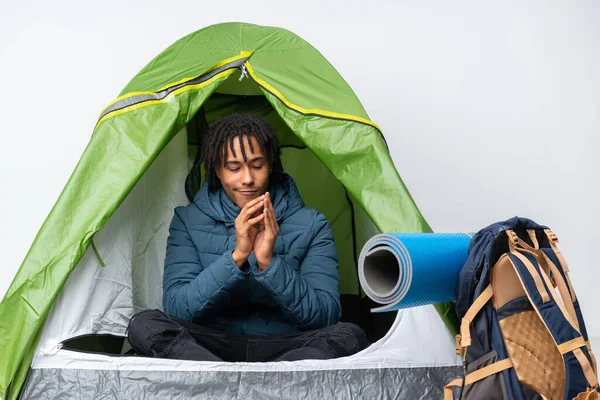 Young african american man inside a camping green tent scheming something
