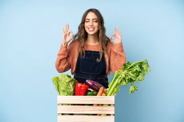 Farmer with freshly picked vegetables in a box in zen pose