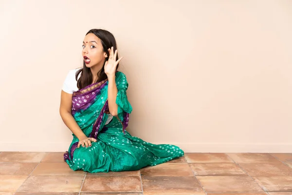 年轻的印度妇女坐在地板上 用手捂住耳朵 听着什么 — 图库照片