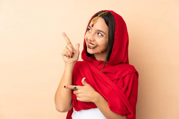 Młoda Hinduska Kobieta Odizolowana Beżowym Tle Wskazując Palcem Wskazującym Świetny — Zdjęcie stockowe