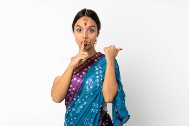 Genç Hintli bir kadın beyaz arka planda izole edilmiş, kenarı işaret ediyor ve sessiz jest yapıyor.