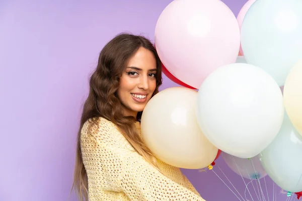 Junge Frau Fängt Viele Luftballons Über Isoliert Auf Lila Hintergrund — Stockfoto