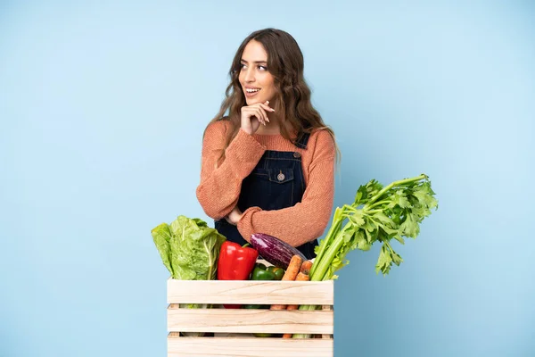 Farmer with freshly picked vegetables in a box looking to the side