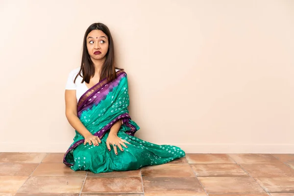 Jonge Indiaanse Vrouw Zitten Vloer Maken Twijfels Gebaar Kijken Kant — Stockfoto