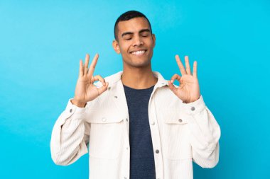 Genç Afro-Amerikan erkek Zen pozunda soyutlanmış mavi arka plan