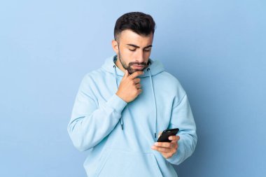 Kafkasyalı bir adam mavi arka plan üzerinde düşünüyor ve bir mesaj gönderiyor.