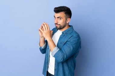 İzole edilmiş mavi arka plan üzerinde beyaz bir adam bir şeyler planlıyor.