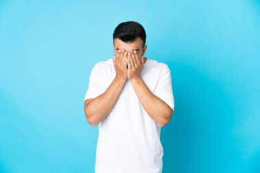 İzole edilmiş mavi arka planı olan, yorgun ve hasta bir yüzü olan beyaz bir adam.