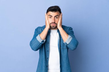 İzole edilmiş mavi arka planı olan beyaz bir adam hayal kırıklığına uğramış ve kulaklarını kapatmış.