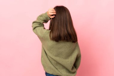 Küçük kız pembe arka planda izole edilmiş ve düşünüyor.